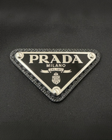 NEWSEDのPRADA Re-Nylonバックパックにあしらわれたアイコニックなブラックのトライアングルロゴプレート