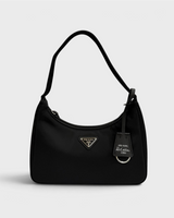 NEWSEDのPRADA Re-Edition 2000 Re-Nylonミニバッグ。ブラックのリサイクルナイロン製で、アイコニックな三角ロゴプレートとチャームが付いたショルダーバッグ。