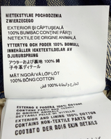 NEWSEDのPRADAデニムジャンプスーツの素材とケア方法が記載された製品タグのクローズアップ