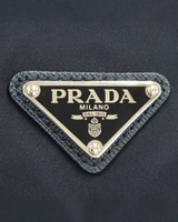 NEWSEDで販売中のPRADA Re-Nylonショルダーバッグにあしらわれたアイコニックなブラックのトライアングルロゴプレート