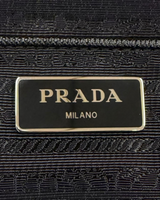 NEWSEDのPRADAバックパックに施されたアイコニックなブラックのトライアングルロゴプレートのクローズアップ