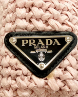 NEWSEDで販売中のPRADAピンクのラフィア素材クロシェトートバッグ、フロントのトライアングルロゴプレートのクローズアップ