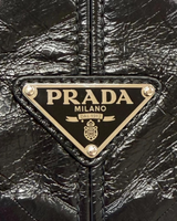 NEWSEDのPRADAブラックソフトルックスレザー製ショルダーバッグに施されたアイコニックなトライアングルロゴプレートのクローズアップ