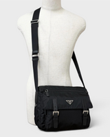 NEWSEDのPRADA Re-Nylonメッセンジャーバッグ。ブラックのリサイクルナイロン製で、トライアングルロゴとバックル付きフラップが特徴的なメンズショルダーバッグ。