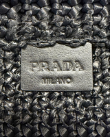 NEWSEDのPRADAクロシェトートバッグ。ブラックのラフィア素材に施されたアイコニックなトライアングルロゴプレートのアップ。