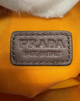 NEWSEDが販売するPRADAのオレンジ色Re-Nylon製フォンポーチに施されたレザー製ブランドロゴタグのクローズアップ